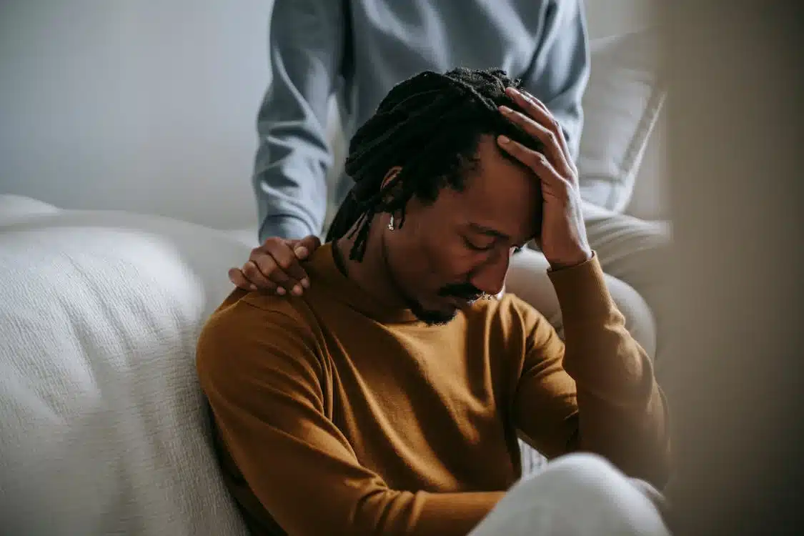Sorrowful-black-man-touching-head-in-dismay-near-supporting-wife