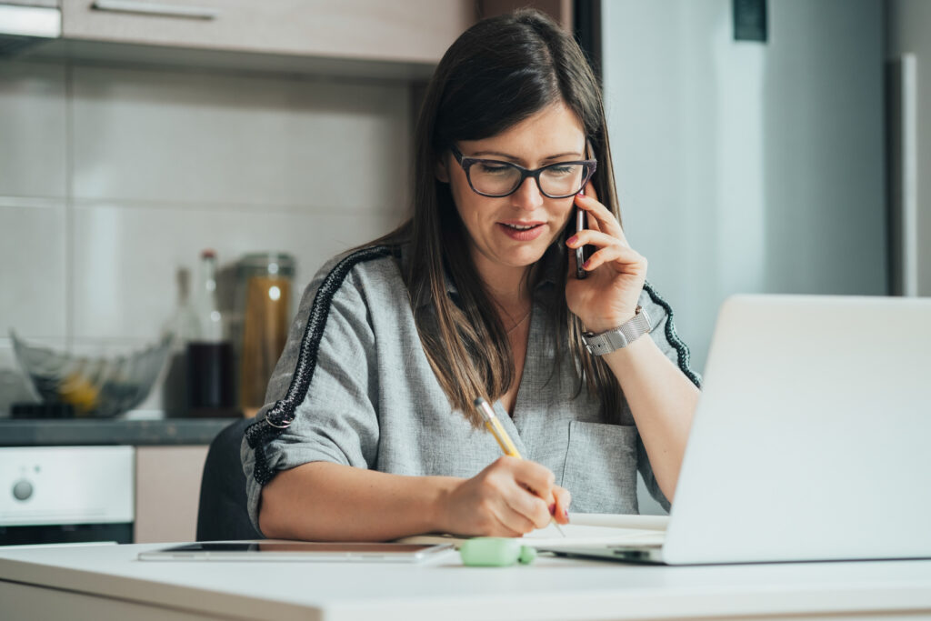 Woman taking notes while calling psychiatry practices, the first step in how to switch psychiatrists