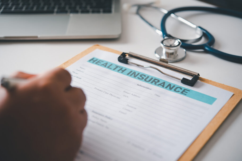 Hand filling out a health insurance form on a clipboard before a first psychiatrist appointment