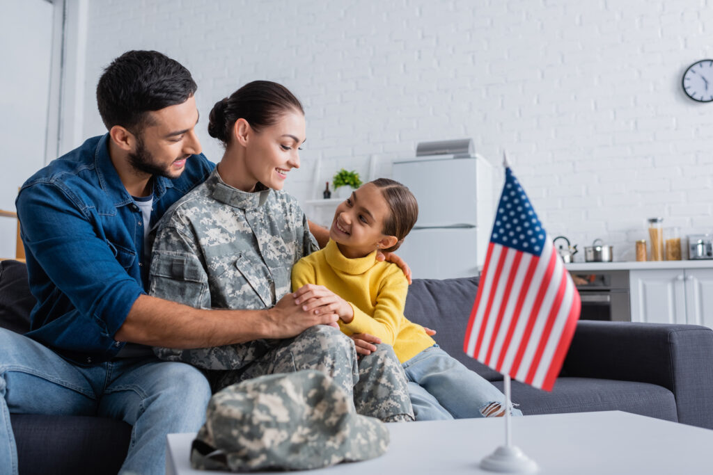Military family at home with a parent in uniform, looking for a TRICARE psychiatrist for adult family members in Maryland