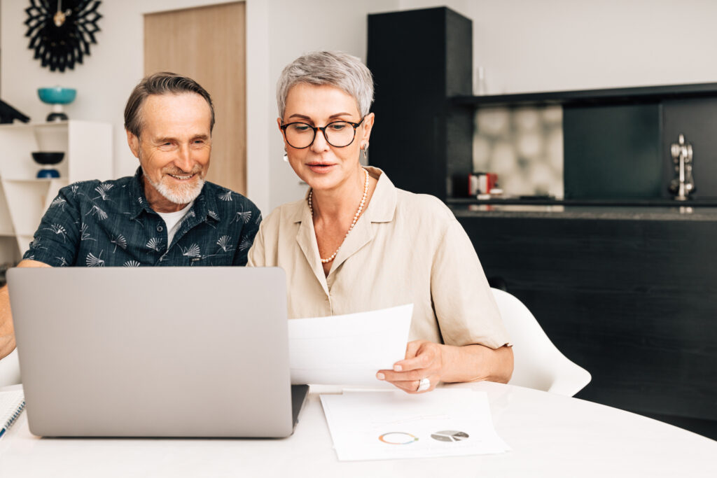 Retired couple reviewing health benefits on a laptop at home before booking with a psychiatrist who accepts TRICARE For Life and Medicare
