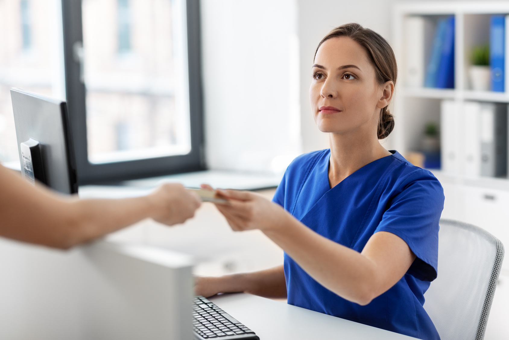 Patient handing an insurance card to front desk staff to verify CareFirst coverage